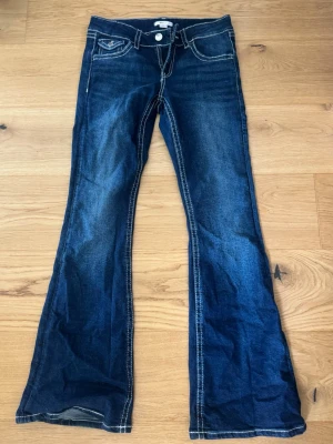 Mörkblå bootcut jeans från Gina Tricot - Säljer ett par mörkblå jeans från Gina Tricots barnavdelning, i storlek 164. Jeansen har bootcut model och låg/medel hög midja. Jag köpte de nya i butik och har använt dom max 3-4 gånger, så skicket är väldigt bra.