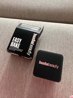 Huda Beauty Easy Bake Pound Cake puder - Säljer ett Huda Beauty Easy Bake Loose Baking & Setting Powder i nyansen Pound Cake. Pudret kommer i en fyrkantig svart burk med rosa logga och tillhörande svart kartong. Perfekt för att fixera foundation och ge en matt finish. Helt oanvänd 