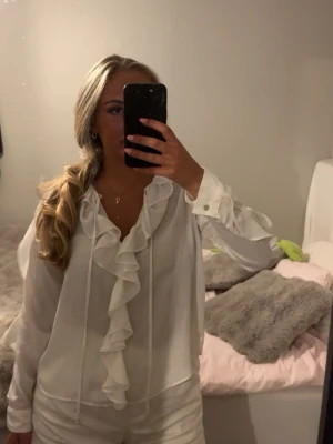 Vit blus med volang och knyt - Säljer en stilren vit blus med långa armar och volanger. Från zara! 