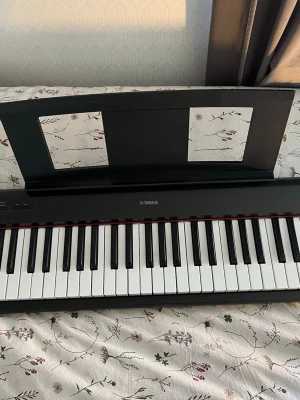 Yamaha digital piano - Säljer ett svart digitalpiano från Yamaha ZT20660 NP-12B med klassisk design och notställ. Pianot har fullstora tangenter i svart och vitt,  passar perfekt för både nybörjare och mer erfarna musiker som vill spela hemma. 