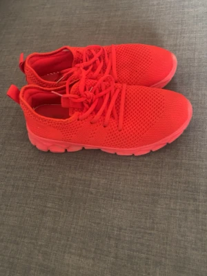 Röda mesh sneakers med snörning - Snygga röda sneakers med ovandel i ventilerande mesh och matchande röda skosnören. Skorna har en chunky sula i samma färg och en låg profil som ger en sportig vibe. Perfekta för dig som vill sticka ut med färg på fötterna.