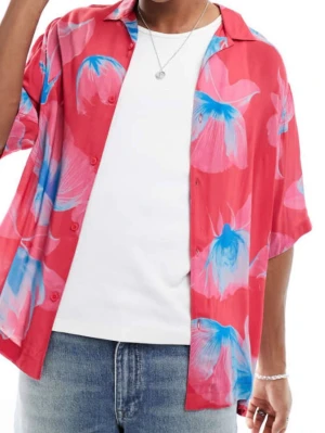 Röd blommig skjorta från Armani Exchange - Säljer en röd skjorta från Armani Exchange med stora blå och rosa blommor. Skjortan har korta ärmar, avslappnad passform och knappar framtill. Perfekt för sommarens alla tillfällen och ger en färgstark vibe.