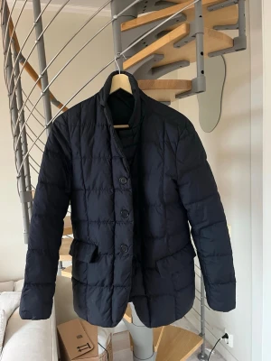 Svart pufferjacka från ASPESI  - Stilren svart pufferjacka med knäppning framtill och två stora fickor. Jackan har quiltat mönster och en rak passform som ger en modern look. Perfekt för våren  tack vare . Inget synligt märke eller defekter finns med jackan. Skick 8/10. Ni som vet om Aspesi vet också hur bra grejer dom gör och sen får man betala därefter också. Nypris på 6990:-