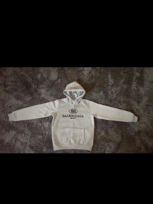 Grå hoodie - Snygg grå hoodie från BB med svart logotyptryck på bröstet och stor magficka. Klassisk huva och ribbade muddar vid ärmslut och nederkant. Perfekt för en avslappnad och trendig streetwear-look.