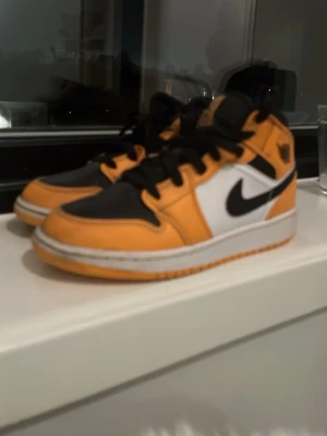 Nike Air Jordan 1 Mid orange/svart - Säljer ett par Nike Air Jordan 1 Mid sneakers i orange, svart och vitt. Skorna har klassisk svart swoosh, vita paneler och orange detaljer. Tjock vit sula och svart snörning. Ikonisk Air Jordan-logga på sidan.vi kan byta skor också snabb affär blir billigare 