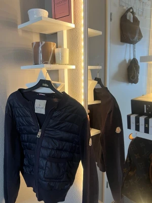 Mörkblå cardiganjacka från Moncler - Super fin cardiganjacka från Moncler🫶🏼Jättefint skick! En liten grej är att man kan dra av drag grejen från dragkedjan (se på sista bild) men egentligen ingen riktig ”defekt” då den fungerar som vanligt! Du kan såklart stänga jackan med dragkedjan!💕Pris kan diskuteras!