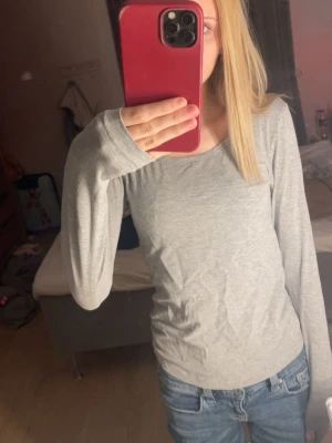 Ljusgrå långärmad topp - En enkel och stilren ljusgrå långärmad topp med rund halsringning. Perfekt att matcha med jeans eller kjol för en clean look. Mjuk och skön mot huden.