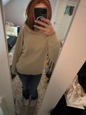 Beige hoodie - Snygg beige hoodie med broderad logga framtill. Klassisk modell med huva och ribbade muddar vid ärmslut och nederkant. Perfekt för en avslappnad och trendig look. Nypris 600kr säljs nu för 290kr men pris kan diskuteras. I storlek M men passar mig som oftast har S. 