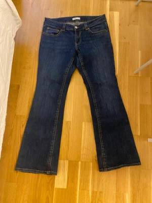 Mörkblå bootcut jeans från Gina tricot - Mörkblå bootcut jeans med orange/bruna sömmar från Gina tricot. Dem är korta i passformen.