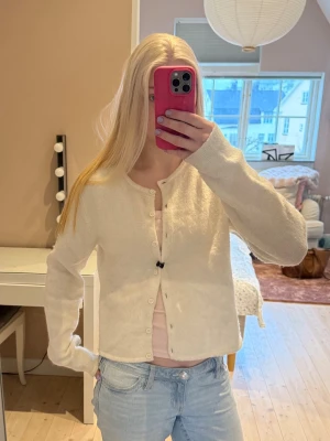 Vit kofta Gina Tricot  - Snygg vit kofta med rund hals och knäppning framtill. Koftan har en enkel och stilren design med långa ärmar och mjukt material. Perfekt att slänga över en topp för en chill look. Från Gina Tricot 