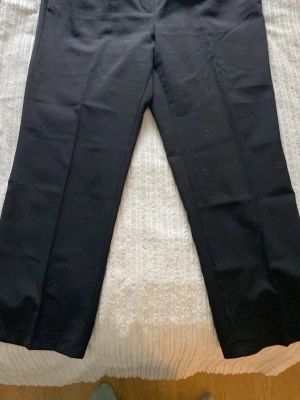 Svarta raka kostymbyxor - Snygga svarta kostymbyxor med rak passform och klassisk look. Byxorna har enkel design utan synliga detaljer och passar perfekt till en stilren outfit. Materialet känns mjukt och följsamt, vilket gör dem bekväma att bära hela dagen.