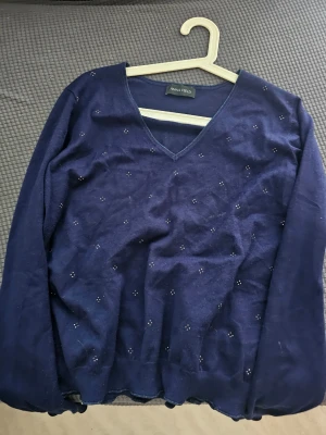 Mörkblå stickad tröja Anna Field - Mörkblå stickad tröja från Anna Field med v-ringning och diskreta små dekorstenar på framsidan. Tröjan har långa ärmar och en mjuk, tunn stickning som passar perfekt till lager på lager. Enkel och stilren design.