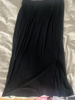 Svart långkjol från Lager 157 - Säljer en svart långkjol från Lager 157 i ribbad struktur. Har en slits, som ny. Jättefin på sommaren, sitter tight. Storlek M