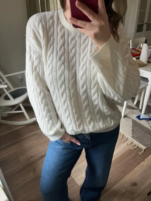Vit kabelstickad tröja - Mysig vit kabelstickad tröja med rund hals och långa ärmar. Tröjan har ett fint flätat mönster och är otroligt mjuk. Hade även denna som L och den satt fint då med!
