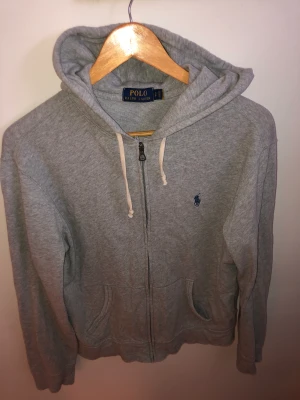 POLO Ralph Lauren hoodie med dragkedja - POLO Ralph Lauren tunn kofta  med dragkedja och huva. Nypris: 1100kr Storlek S passar även M Bra skick inget slitage eller tecken på användning. Hör av dig vid frågor!