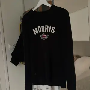 Det är en Morris tröja som är i storleken medium. Tröjan är lite solblek och är mörkblå ifrån grunden.