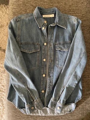 Jeansjacka  - Blå jeansjacka i nytt skick. Modellen är lite som en jeansskjorta och ganska tunt tyg Köparen står för frakten