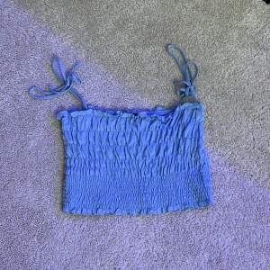 Ett gulligt blått linne i storlek M med axelband man kan knyta och anpassa lite själv.