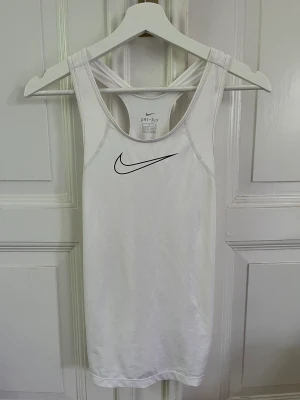 Vitt nike träningslinne  - Vitt träningslinne från Nike med stort märke. I storlek XL från barnavdelningen, men stor i storlek så som xs,s. I bra skick🥰