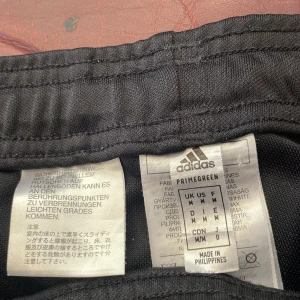 Adidas byxor  - En svart adidas byxor med dragkedja vid benen.