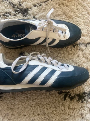Marinblåa sneakers från Adidas  - Ett par helt oanvända sneakers från Adidas i jättefin mörkblå färg! Köpta för 35$ men säljs för 100kr! 