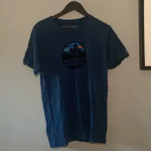 Marinblå Patagonia t-shirt med cirkulärt tryck på bröstet Modell: Slim fit  Nypris: 400kr