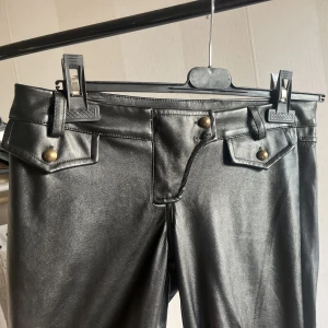 Lågmidjade läderbyxor bootcut - Svincoola läderbyxor med gulddetaljer, lågmidjade. Typ helt i nyskick! Bootcut/straight leg