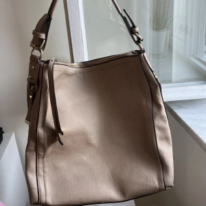 Väska i skinnimitation  - Superfräsch väska från märket Oasis (köpt på accent)! Rymlig med bra fickor och i en brun/beige färg. 