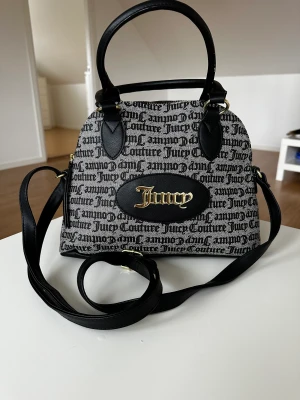 Juicy couture väska  - Den är oanvänd så den är i ett fint skick. Den är ca 25 cm i längden och den bredaste delen är ca 30 cm. 