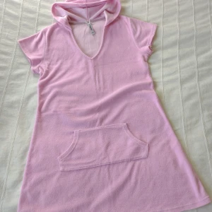 Rosa tunika/klänning med huva - Loungewear by Unia - storlek M - Rosa tunika/klänning med huva från Loungewear by Unia. Storlek M. Frotteliknande material - 80% bomull 20% polyester.