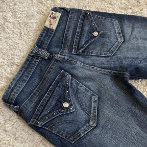 Vintage jeans - HAR LAGT UPP NYTT INLÄGG FÖR GRATIS FRAKT! 😍 Från Madonna, lågmidjad och bootcut modell. Har snygga detaljer bak och fram, OBS en den rhinestones har lossnat. ❤️ Innerben:     76cm, midja rakt över: 36cm. Jag är 165, kan fixa fler mått. 🫶 