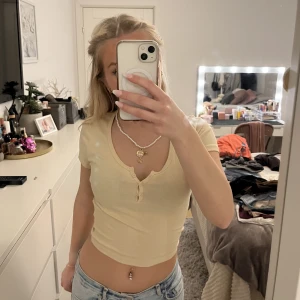 Gul/beige t-shirt - Säljer denna gul/beiga t-shirten från Gina Tricot som inte kommer till användning. Den har 3 styckna knappar💗 