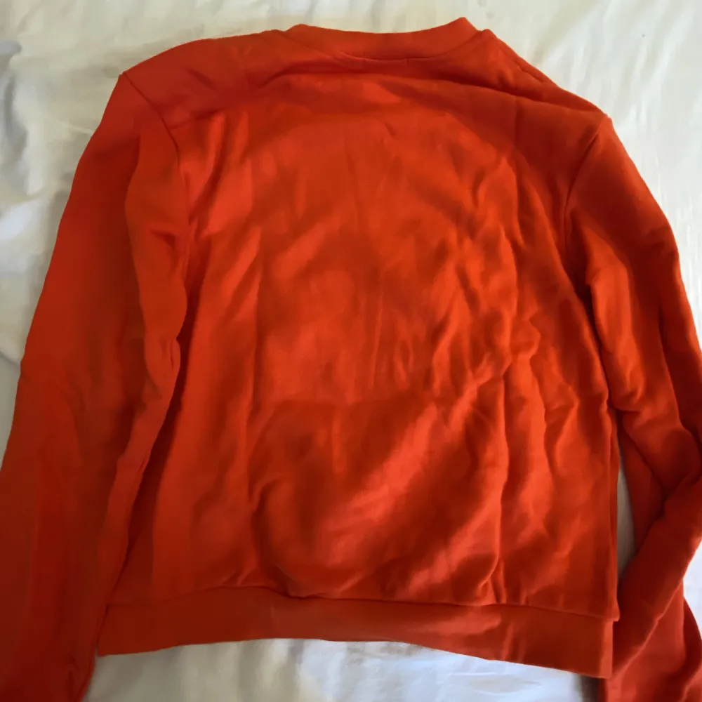 En röd/orange hoodie utan luva. Har lite fläckar på framsidan men dom syns inte jättemycket. Annars jätte skön, inte använd så mycket så den är i gott skick. Säljer då den inte kommer till användning längre . Hoodies.