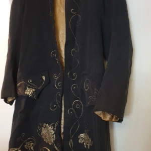 Lajv rock - Tycks som att axelvsddar blivit undanvikta och hålls borta med ett par sömmar. Det kan jag såklart rätta till. Denna rock tycks vara handsydd. Rejält sammetslikt material och med ett foder i guldig satin. Utsmyckning även medbroderingar i guldfärgad tråd.