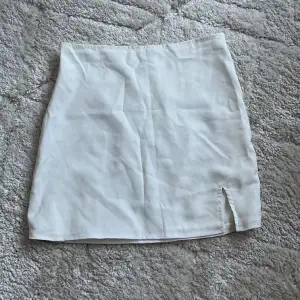 Kort vit kjol med slits, använd fåtal gånger men har sytt in den vid höften och på längden. 