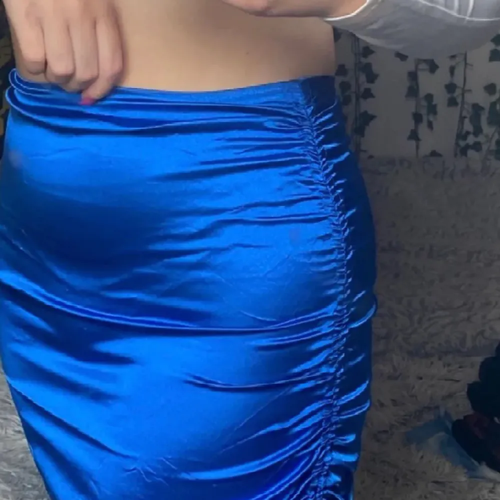 Kort blå kjol med snöre på sidan. Kjolar.