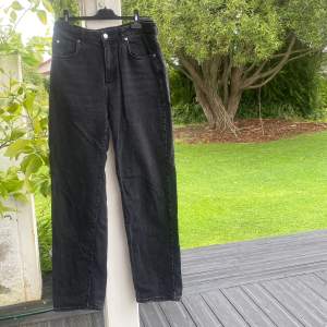 svarta jeans med högmidja och straight i benen, fickor bak och fram,  storlek i midja och ben syns i bild