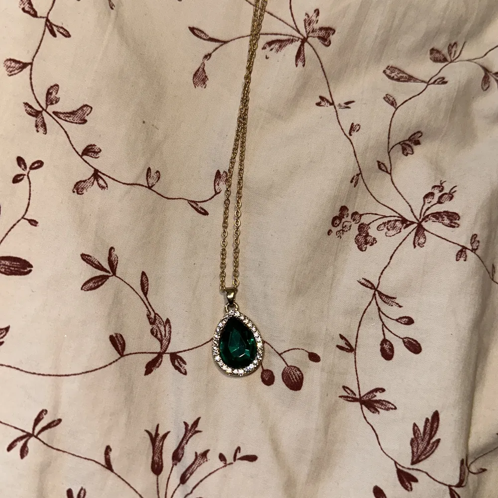 Säljer detta fina halsband men ett hänge i form av en smaragd liknande i mitten och små diamanter runt. Accessoarer.