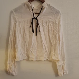 Oanvänd Blus med spets krage från H&M.  - Oanvänd Blus med spets krage, knappar och snöre från H&M i storlek 36. Är i bra skick. 