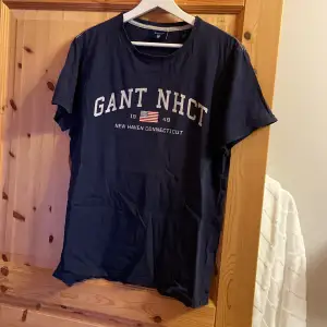 Gant T-shirt i storlek M. Den är i använt skick och har spruckit lite i texten på framsidan, inget som man tänker på. Finns två små hål som knappt syns. 