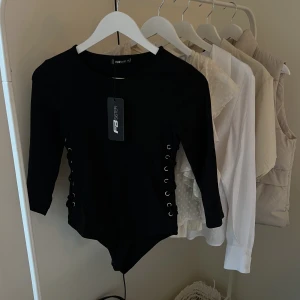 Svart body från New Yorker - säljer denna oanvända body från New Yorker med snörning på sidan, helt oanvänd med lapp kvar, strl S🤍