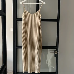 Randig midiklänning  - Snygg klänning från Mango. Beige och vit randig med slits fram.