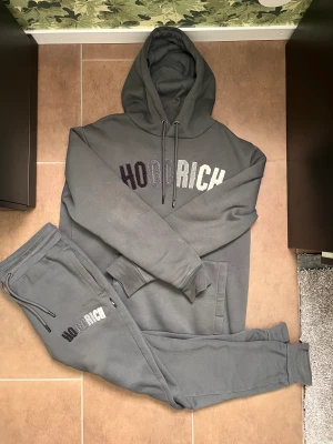 Hoodrich grå kaws set - Tröjan är M och byxorna är S. Den är i nästan helt ny skick och är använt 3 gånger. Kontakta för frågor!