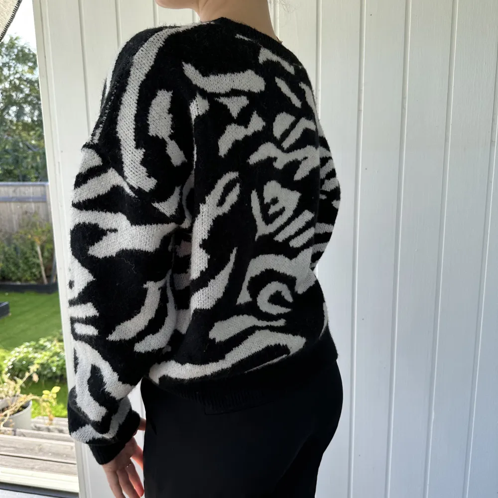 En stickad tröja i väldigt mjukt material. I vitt och svart zebra mönster. . Stickat.