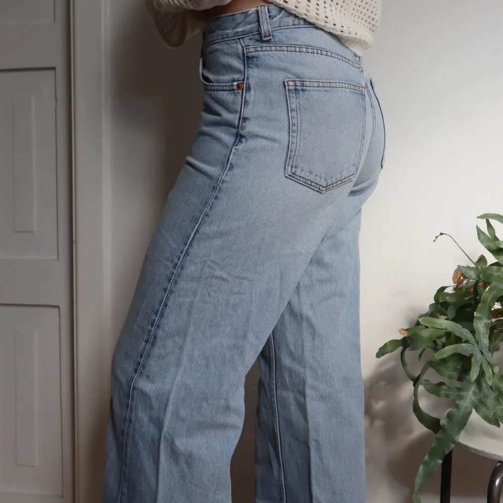 Ljusblåa jeans från Monki. Högmidjade och vida i benen (modellen är 172cm). Har ett snyggt hål som detalj på ena benet. Bra skick! Säljer för jag ej kan ha dom längre 🫧. Jeans & Byxor.