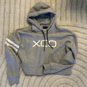 Kort hoodie  - En hoodie i kort modell med luva. Grå med snygga vita tryck!. Skönt tyg på insidan. Storlek M