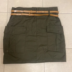Grön kjol  - Cool kjol i lite militär stil. Minimalt använd, dock har en hake ramlat av. Stl 40. 