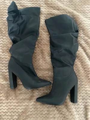 Boots med klack, klackskor  - Svarta boots med klack. Skorna går upp till halva vaden. 