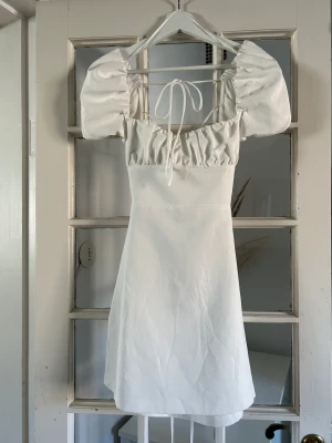 Vit klänning med snörning i ryggen - Jättesöt klänning från Zara i stl XS med snörning i ryggen. Materialet känns och ser ut som linne. Jättefint skick! Enbart provad.