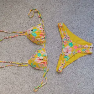 Gul blommig mönstrad bikini från Bik Bok. Underdelen är i storlek M och överdelen XL.